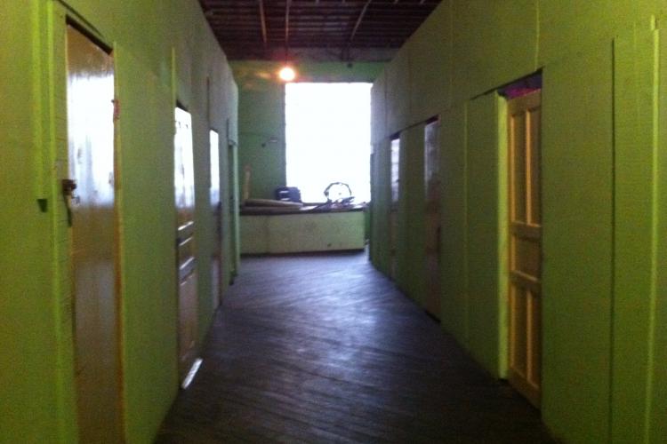 Interior de um edifício ocupado. A grande antiga sala de entrada foi transformada em quartos pequenos, instalando paredes de madeira compensada. Crédito: Heike Drotbohm