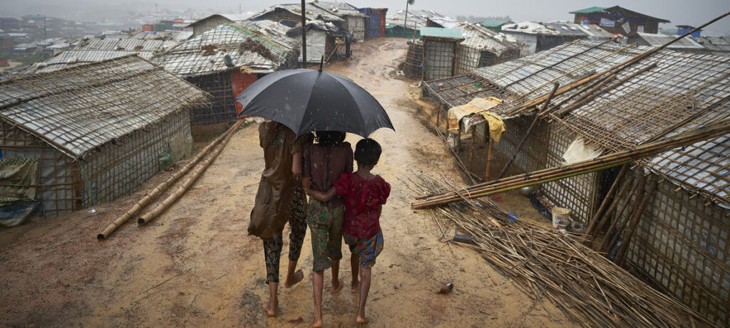 Refugiados rohingya caminham por uma trilha durante uma forte chuva de monções no campo de refugiados de Kutupalong, no distrito de Cox’s Bazar, em Bangladesh. 
(Foto: David Azia/ACNUR)