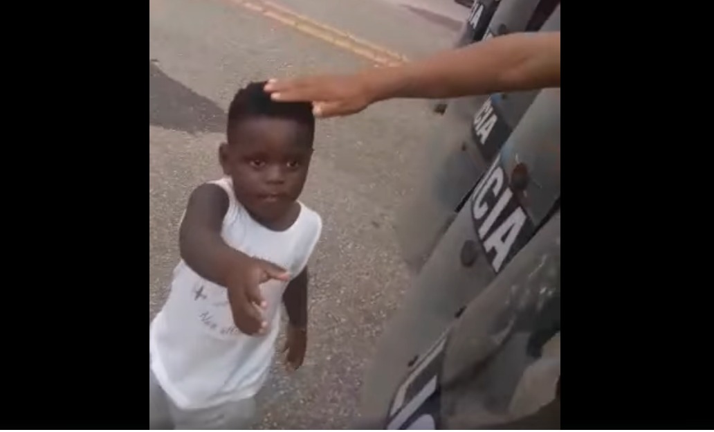 Criança haitiana estende a mão para policiais durante protesto na fronteira entre Brasil e Peru, no estado do Acre